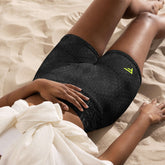 Woman wearing black high-waisted training shorts on sand, showcasing comfortable fit and stylish design.