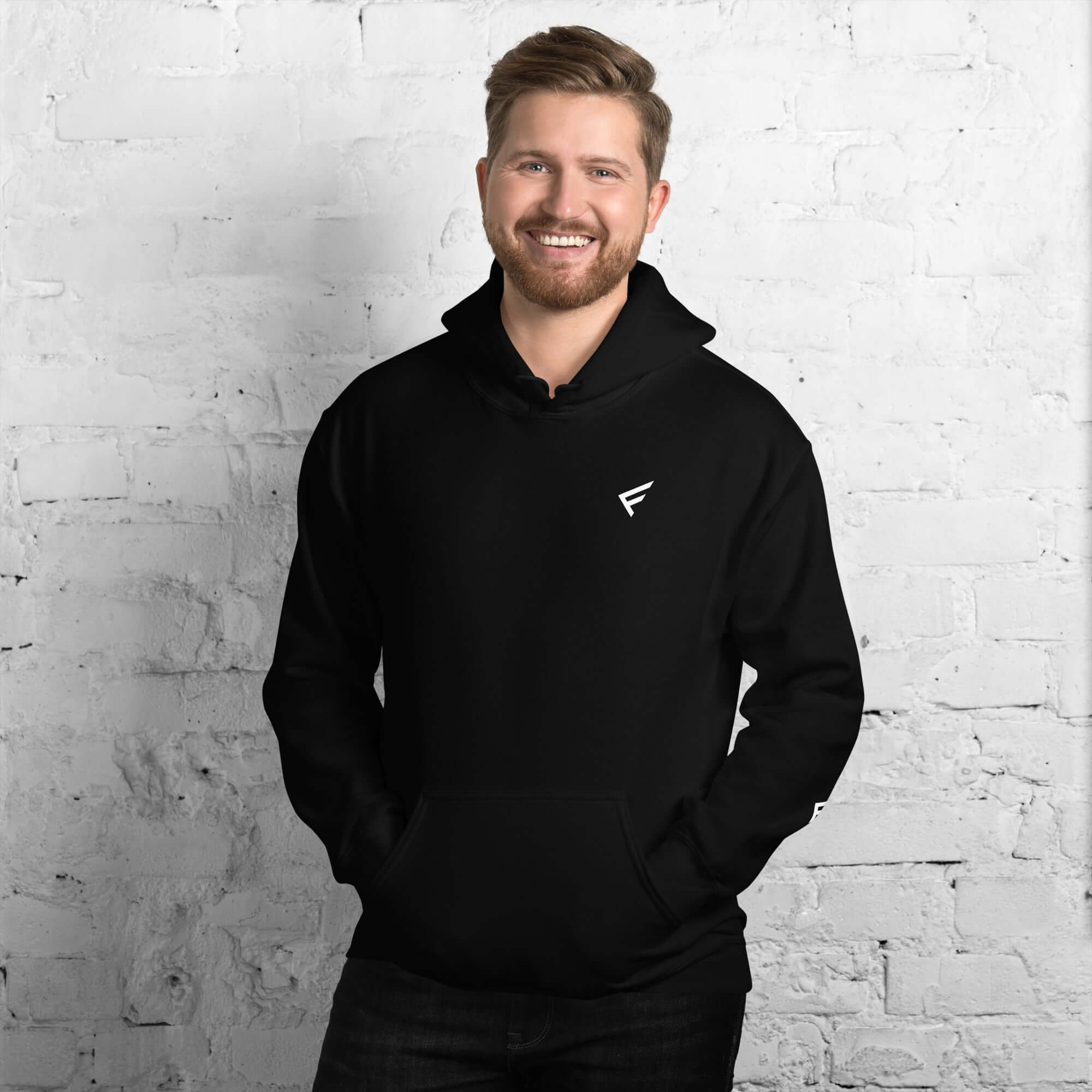 Man wearing a black hoodie from the Core Collection, showcasing comfort and style against a brick wall.